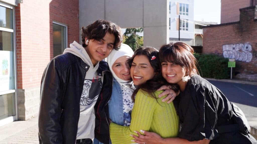 Yasmine, Nada and family holding each other close and smiling at the camera