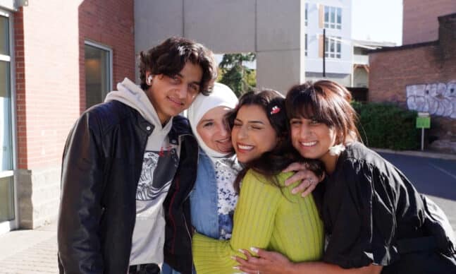 Yasmine, Nada and family holding each other close and smiling at the camera